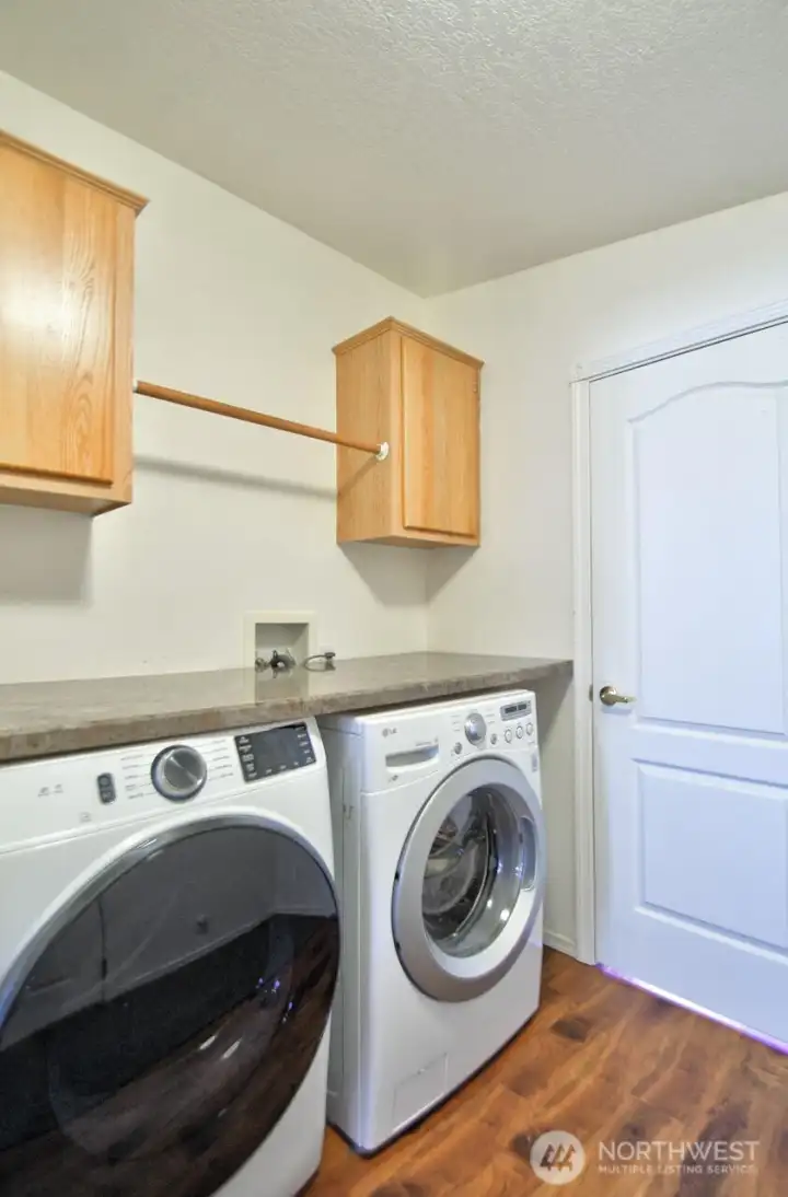 Utility room adjoins kitchen and garage. Front load washer, dryer plus cabinets and clothing rack.