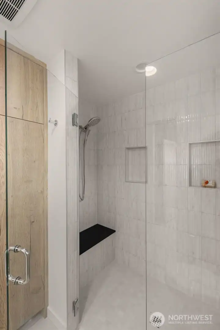 Rain shower framed by glass enclosure takes center stage while a wide vanity and polished fixtures enhance the luxury of this primary bathroom.