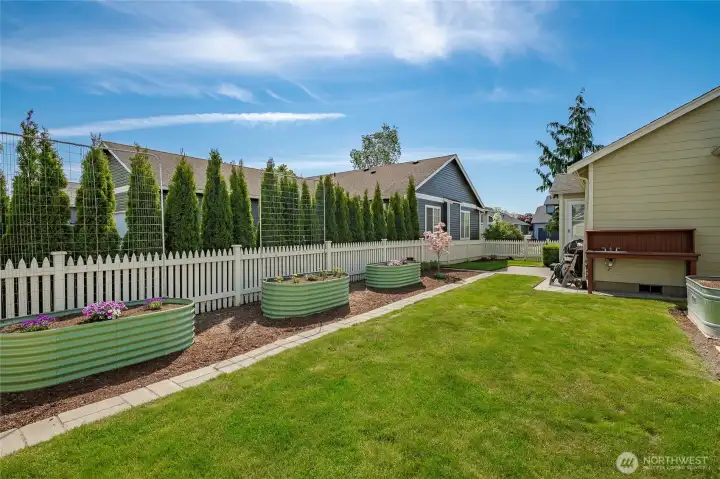 Fully fenced backyard with raised garden beds.