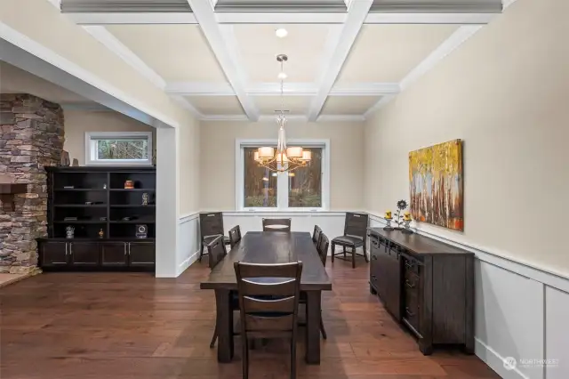 Grand dining room boasting coffered ceilings, wainscotting and elegant chandelier.