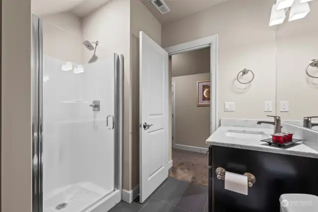 Upstairs 3/4 bathroom featuring sleek dark cabinets and a stylish quartz vanity.