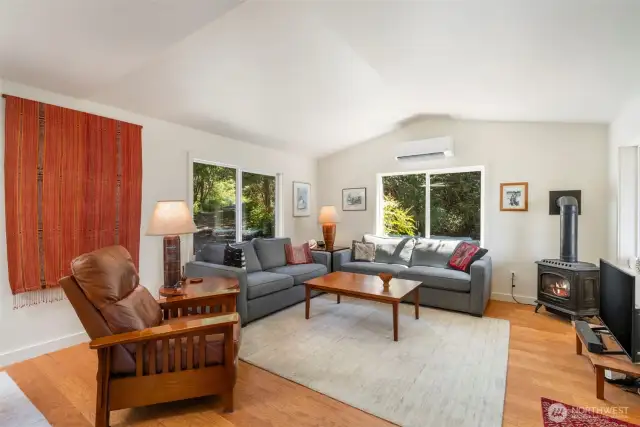 Light and bright living room with propane stove in corner.  Floors are engineered hardwood.