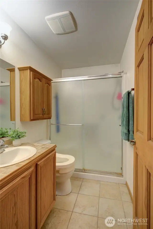 Three-quarter bathroom with easy, step-in shower and ceramic tile floors for easy care.