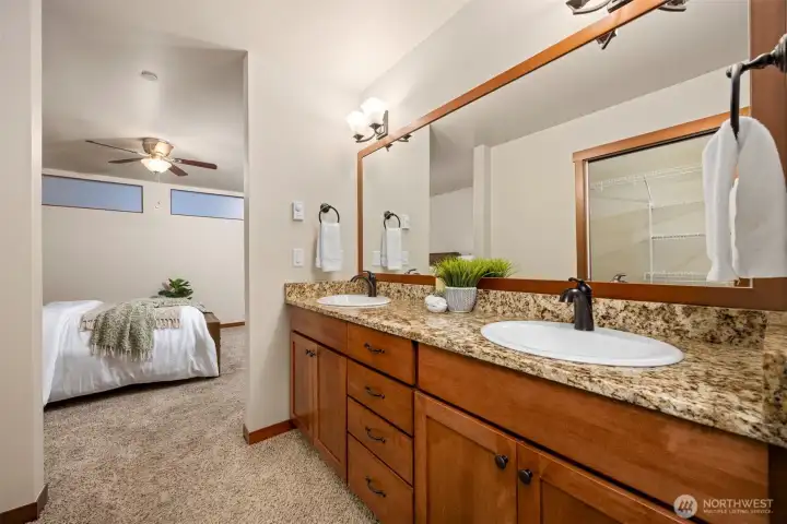 Dual vanities with granite counters and beautiful wood cabinetry (and the walk in closet behind). The ceiling fan helps keep the bedroom comfortable!