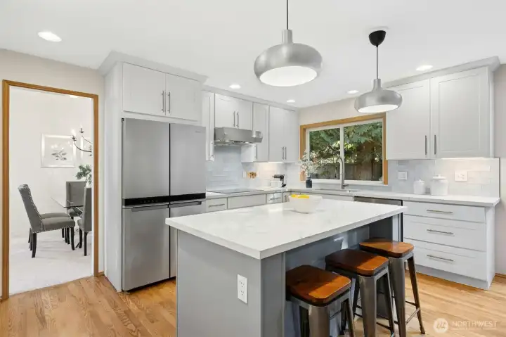 Stunningly updated kitchen featuring sleek stainless steel appliances and a sprawling quartz center island and counters, perfect for hosting festive gatherings.