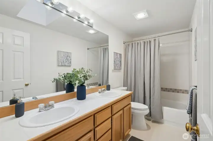 Guest bath with dual sinks and another light filling skylight.