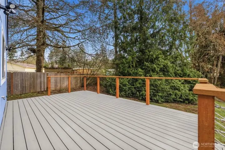 Spacious deck overlooking a peaceful, tree-lined backyard that offers added privacy and a natural setting.