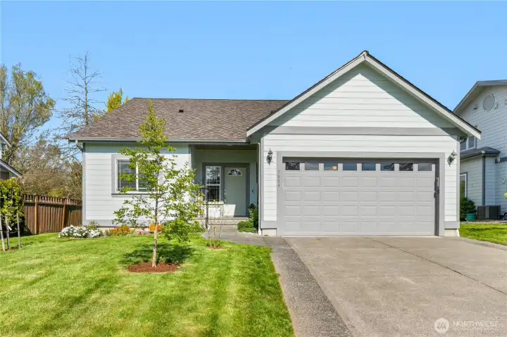 Front exterior with attached garage, wide driveway, and maintained landscaping in a golf course community.