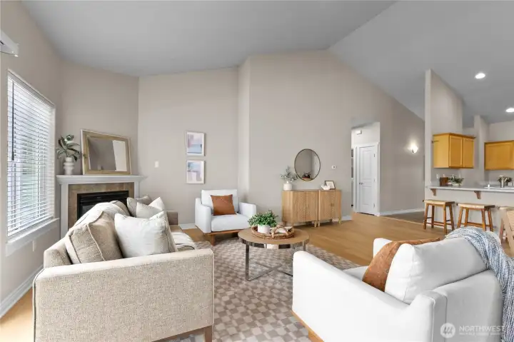 Spacious living room with vaulted ceiling, recessed lighting, and fireplace as focal point