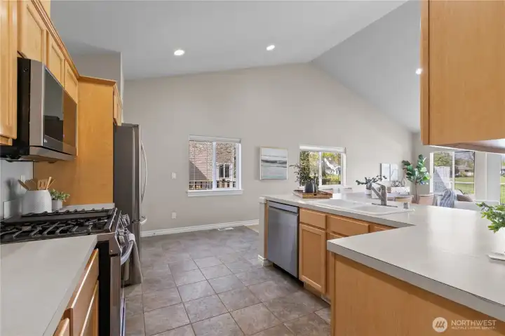 Functional kitchen layout with gas range, microwave, and continuous counter space