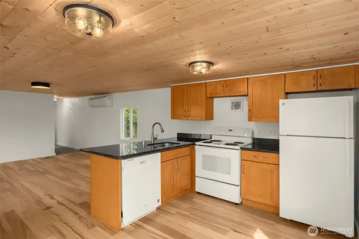 A kitchen that welcomes you in - warm ceilings, updated lighting, dark counters, and room to cook.