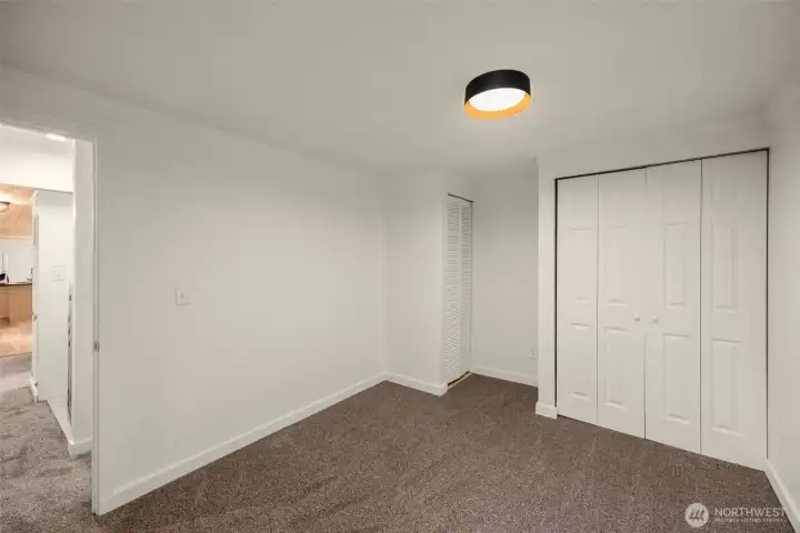 Primary bedroom with new carpet, fresh paint, and updated lighting.