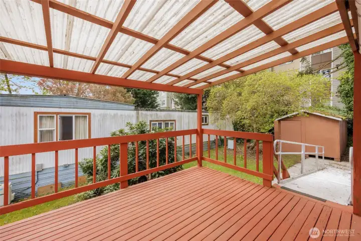 Another view of the spacious covered deck with the ADA-accessible ramp and storage shed in the background