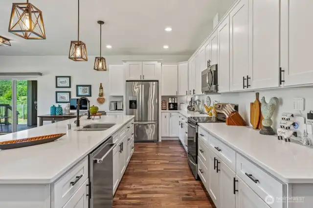 This kitchen is simply amazing! White cabinetry with crown moulding, black hardware, quartz countertops, stainless upgraded appliance package (brand new high-end dishwasher).  Pretty pendants and an ISLAND that is one heck of a seating bar - room for 8 at well over 10' long!!