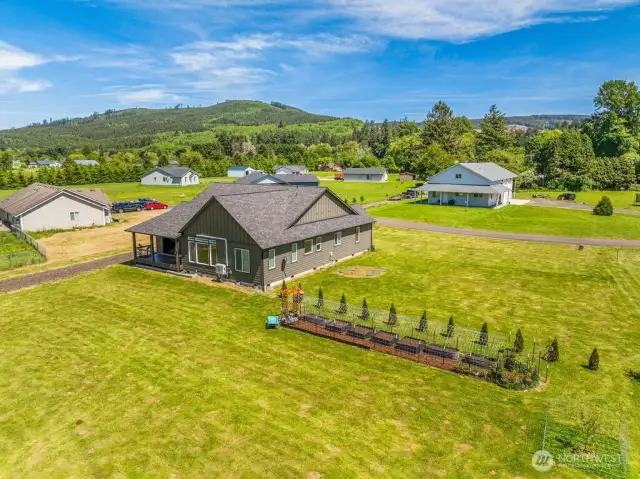 Drone view from rear of home; 7 raised beds, mulch path in entire enclosure, protected by cattle panels. Nice boundary of privacy trees taking shape!