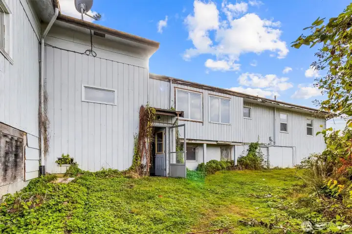 Rear exterior of the home with walkout access and surrounding greenery.
