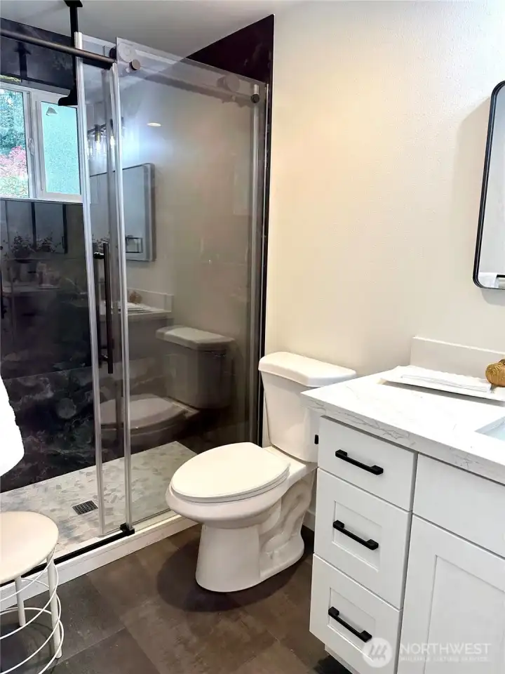 Modern ensuite bathroom featuring stylish titles and spacious walk-in-shower.
