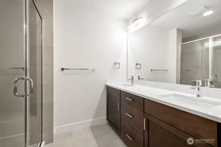 Primary bath with double sinks, large shower, and walk in closet