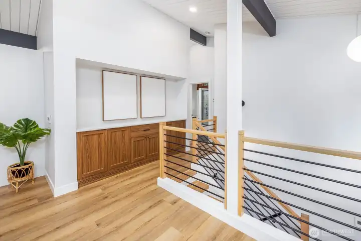 Just up the stairs from the entry, notice your built in cabinets and shelving for your artistic influences. The cabinets and shelves keep your home neat and tidy.  Open railings add to the modern elements.