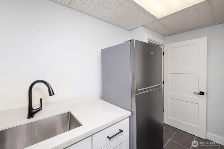 Full sink and fridge in lower level kitchenette.