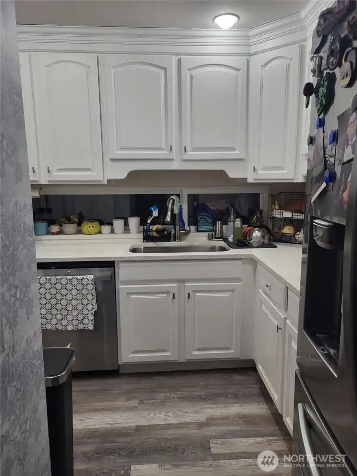 Entrance to L shaped kitchen with windows to the fenced patio space.