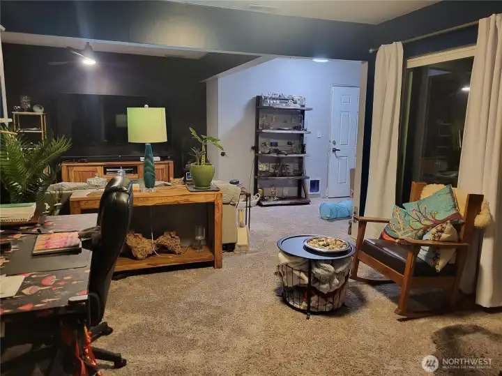 Living room from the kitchen. Fenced patio to the right out of the sliding doors. This room has another gas fireplace. Garage entrance in the corner.