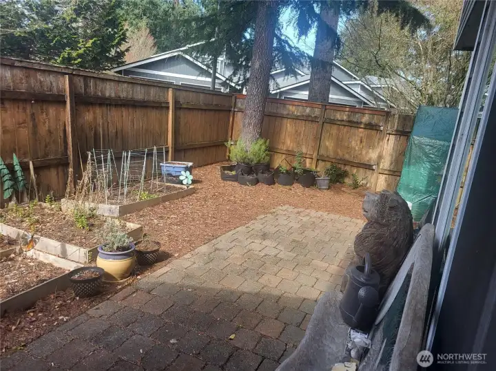 Outdoor patio space with cement slab. Fence has gate to the parking lot and mailboxes.