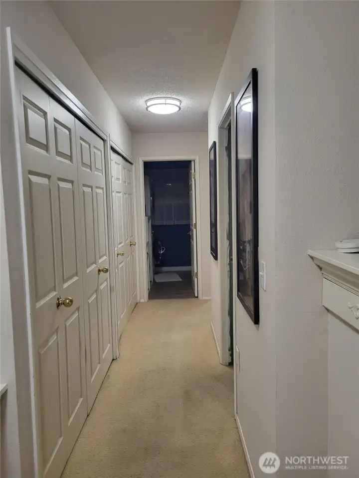 Hallway to laundry room, bathroom to the left and closet space to the right. One closet holds new water heater and furnace.
