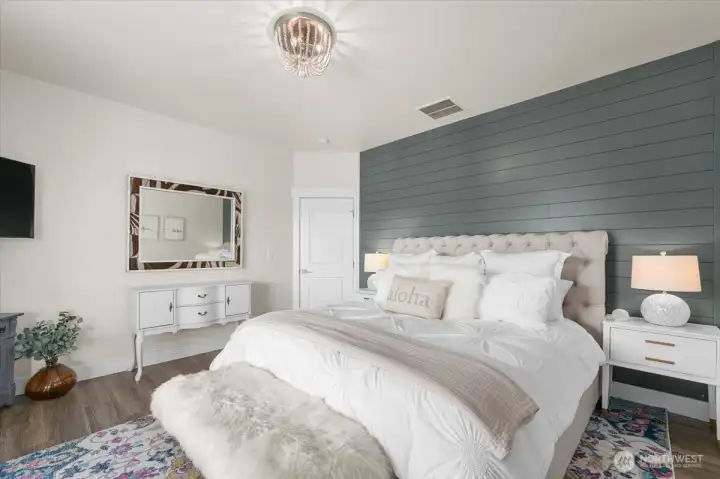 Inviting primary suite with custom wood accent wall details, soft natural light, and seamless access to the deck and ensuite bath.