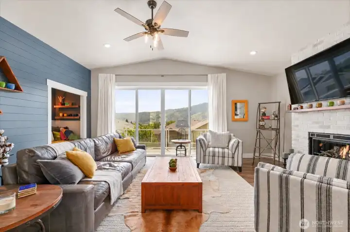 Inviting living room with vaulted ceilings, fireplace feature, and layered design details that create a warm and inviting feel while being able to enjoy the beautiful views year-round.