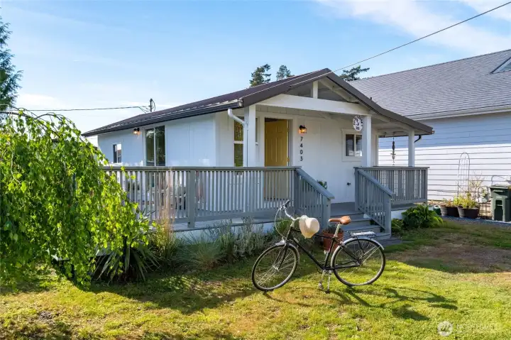 Charming single-level cottage with a welcoming covered front porch, classic white siding, and thoughtful landscaping—perfect for enjoying quiet mornings or greeting neighbors.