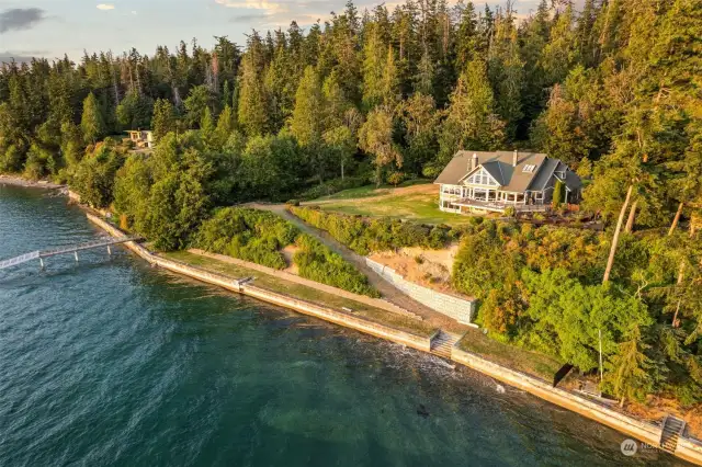 This breathtaking drone shot showcases a magnificent waterfront estate on Whidbey Island, spanning over 7 lush acres. The expansive 6,120 sq ft home, nestled amidst verdant landscapes, boasts six luxurious bedrooms and offers 254 feet of private waterfront.