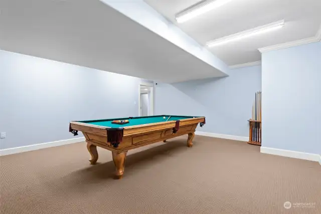 A classic pool table serves as the focal point, offering endless hours of fun and friendly competition. The spacious layout ensures ample room for play and socializing, creating a perfect setting for gatherings with family and friends.