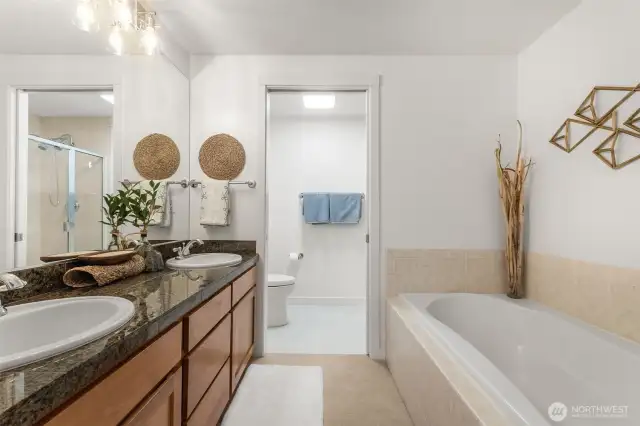 Spacious primary ensuite featuring a relaxing soaking tub, dual sinks, and refreshed vanity lighting for a bright, modern feel.