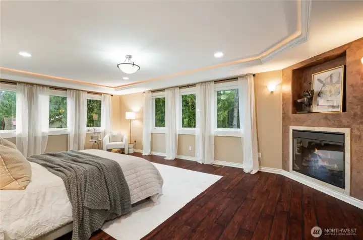 Grand primary suite with fireplace and windows overlooking the scenery.