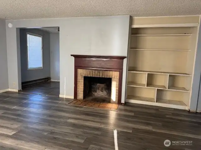 Spacious living room with wood, wood burning fireplace and built-in shelving.