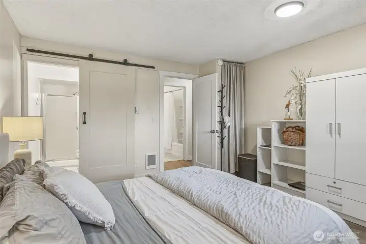 Primary bedroom with ensuite 3/4 bath on the left, looking towards guest bath across the hall (upper middle of picture). The electric water heater is behind the curtain to the right of the door to the hall.