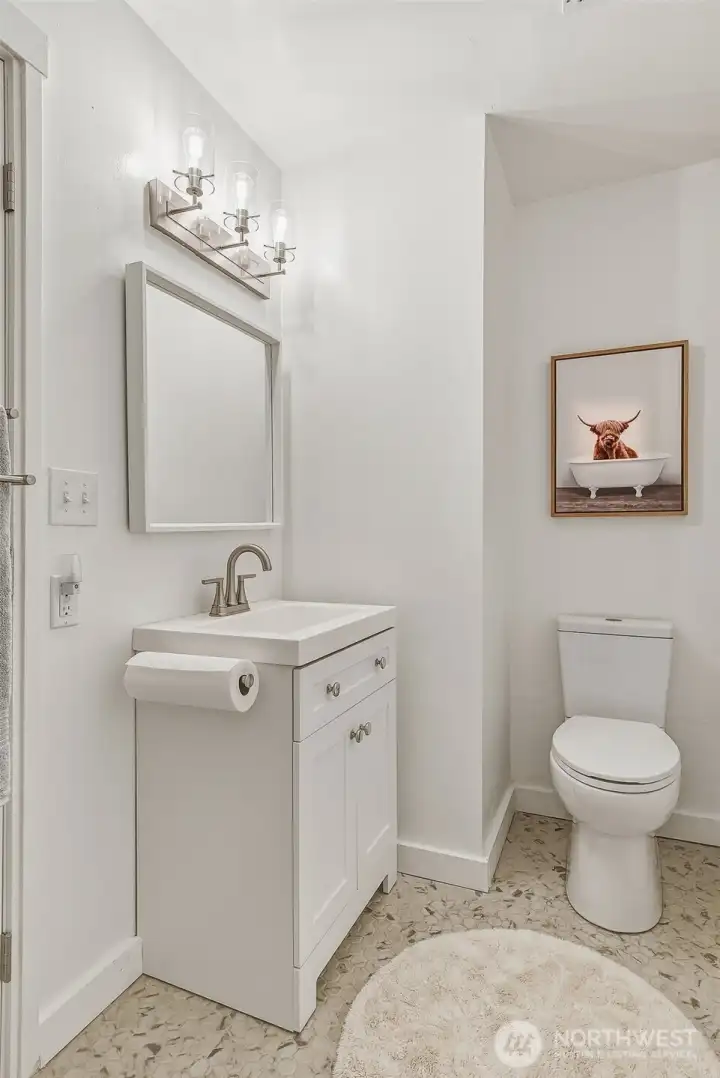 Updated guest bath has a new vanity, toilet, light, and tile floor