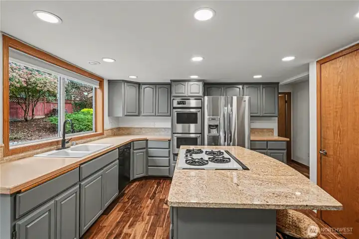 The kitchen is a standout with ample cabinetry, a walk-in pantry, granite island with gas cooktop, double ovens, and updated appliances.