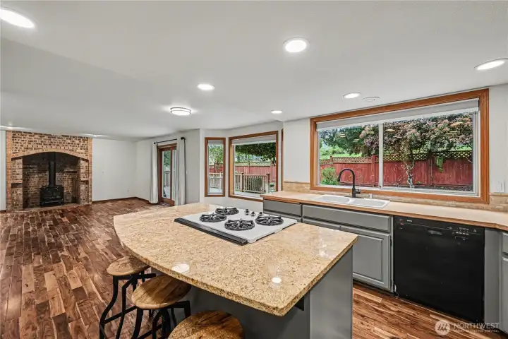 Oversized kitchen window frames a picturesque view of the backyard.