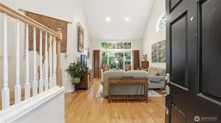 The entry way is impressive with beautiful hardwood floors, a white enamel open stairway and wonderful soaring ceilings.