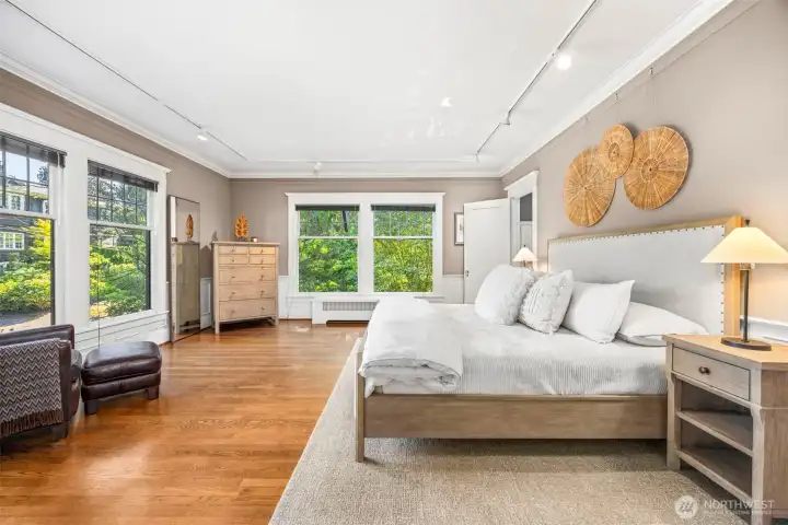 This generous bedroom suite serves as a peaceful retreat, framed by rich hardwoods and lush treetop views.