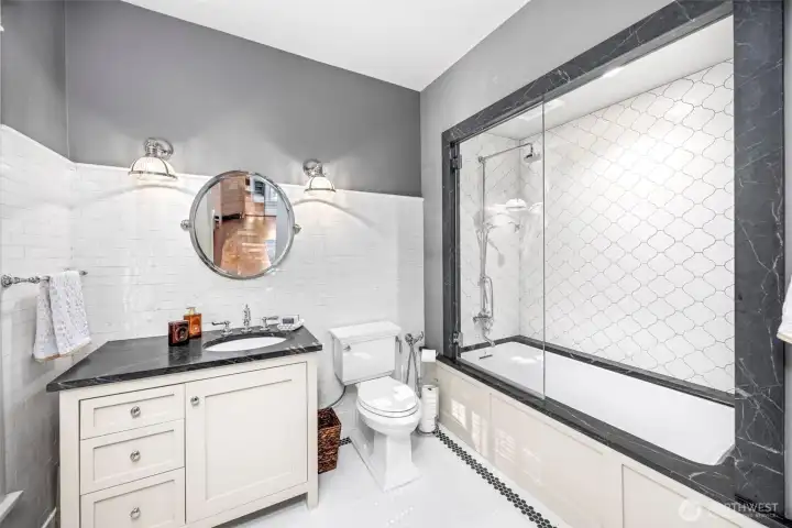 Original subway tile pairs with dramatic dark stone accents to create a sophisticated, timeless bath.