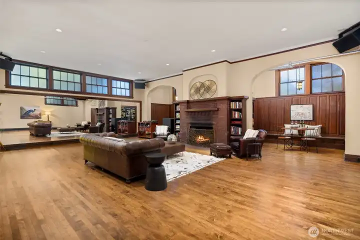 The expansive lower-level ballroom features rich wood paneling and a classic brick hearth.