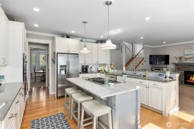 Center island with gas cooktop, upgraded pendent lighting and counter seating. Walk-in pantry located in hallway leading to formal dining room.