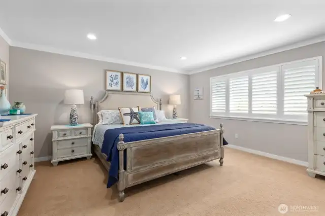 Primary bedroom with golf course views, recessed lighting, crown molding and custom plantation shutters.