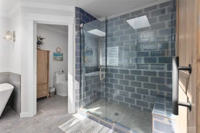 Custom tile shower with upgraded hardware, bench and frameless glass door.
