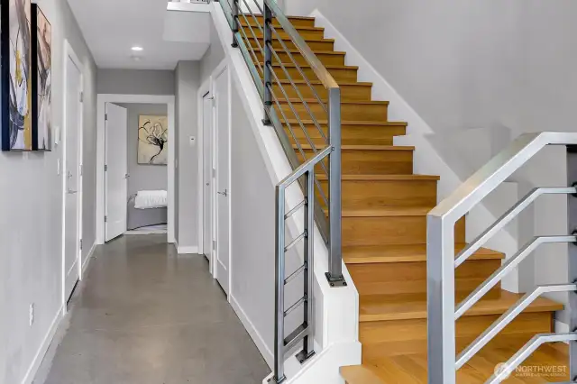 Inviting entry foyer with low maintenance polished concrete walkway heading to separate 3rd bedroom with attached 3/4 bath. Quality hardwood stairs with sleek metal handrail going to the main living level