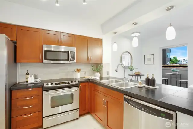 The kitchen features overscale tile flooring, durable quartz countertops, 6" tile backsplash, and rich shaker-style cabinetry