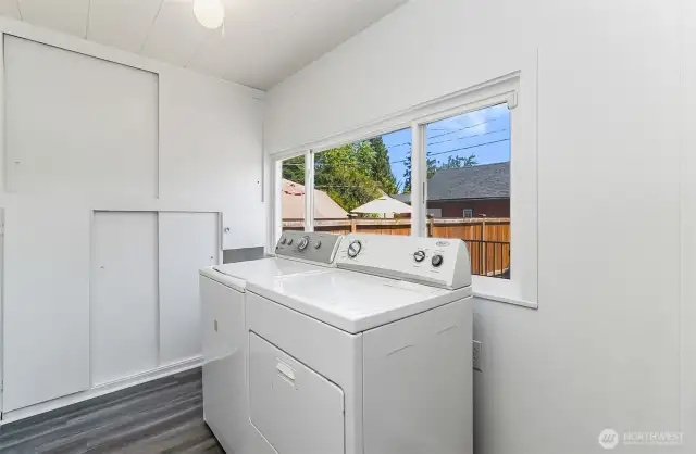 The bright and cheerful laundry room with wall of cabinets.